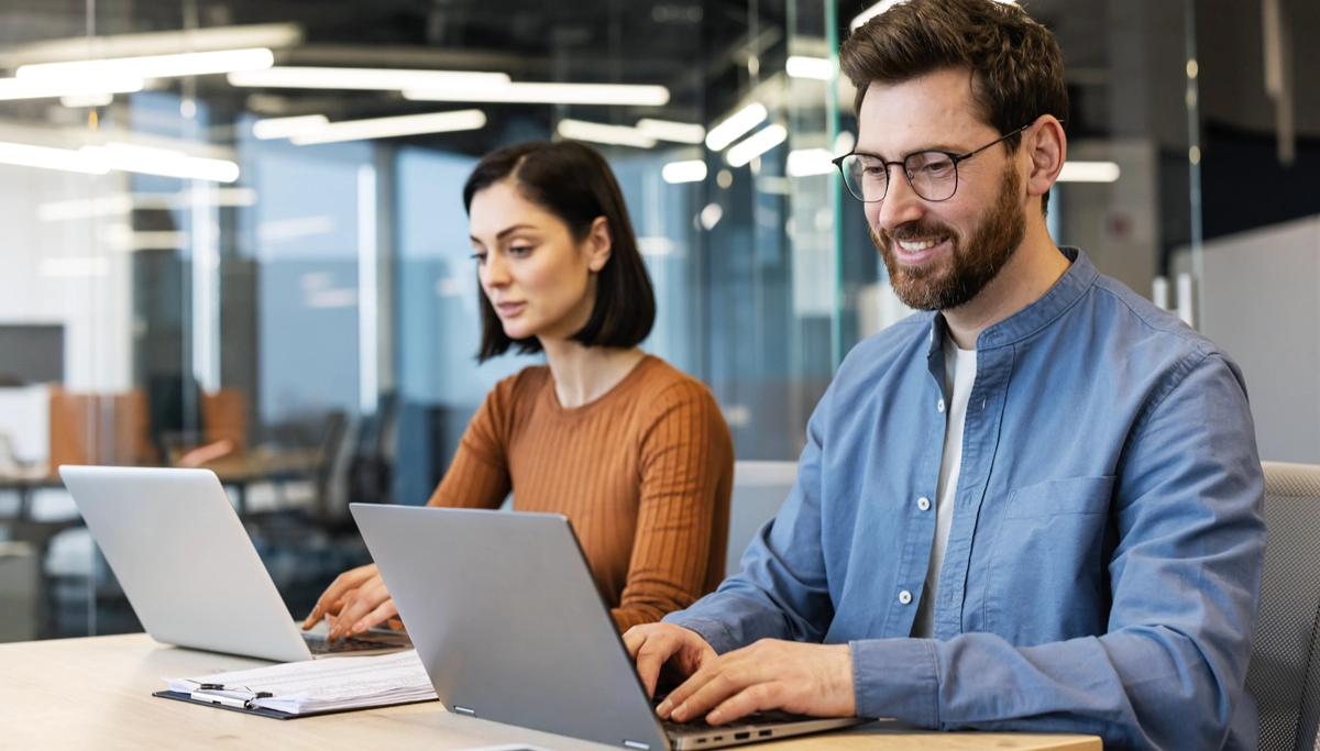 man-and-woman-working-in-office-on-laptops-1200x683.webp