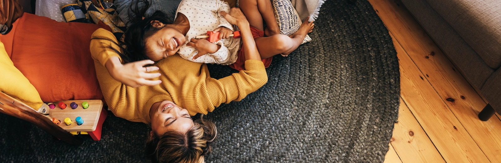 mom-and-daughter-laughing-on-the-floor-1600x522.webp