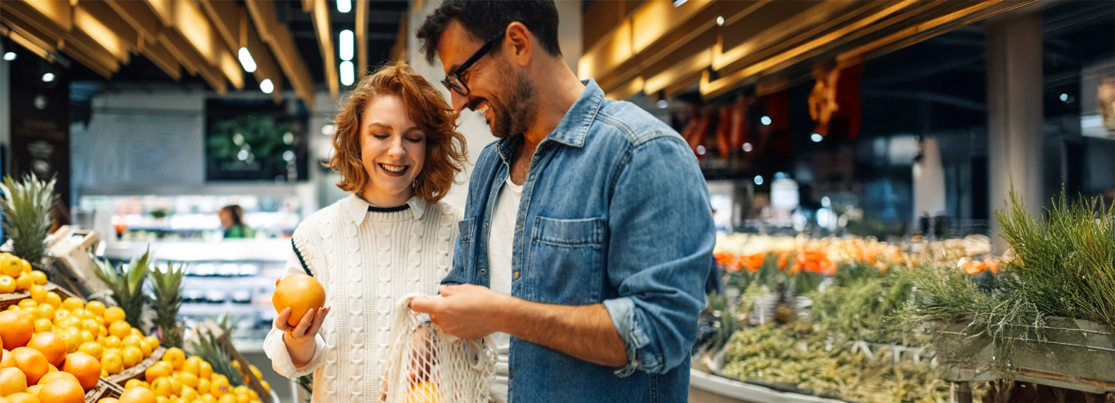 A young couple is grocery shopping in a well-lit supermarket